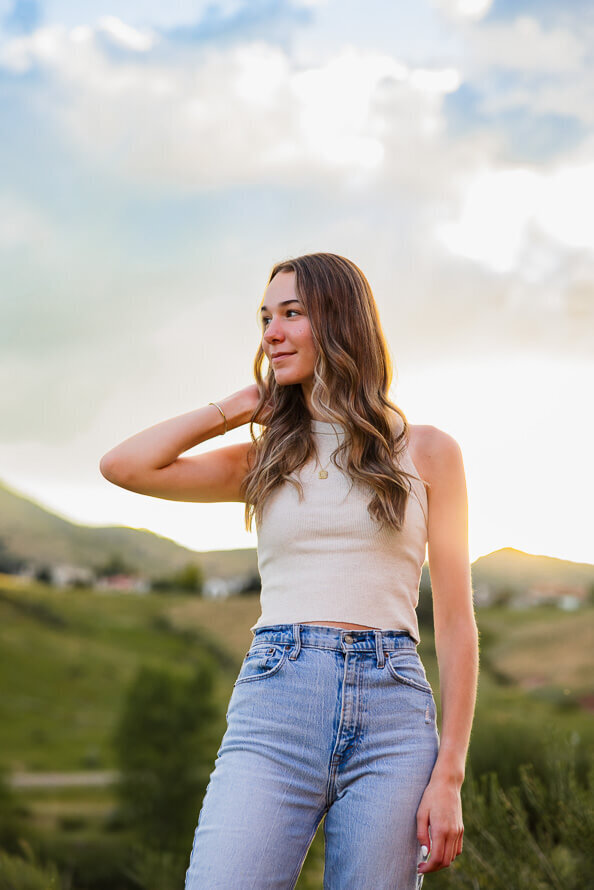 Girl with hand behind head looks off into the distance.
