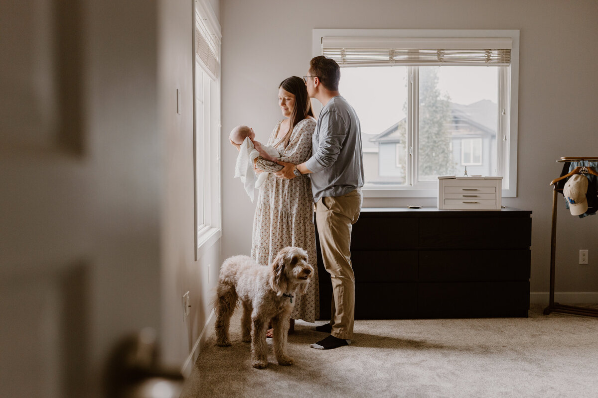 Parents holding newborn with dog