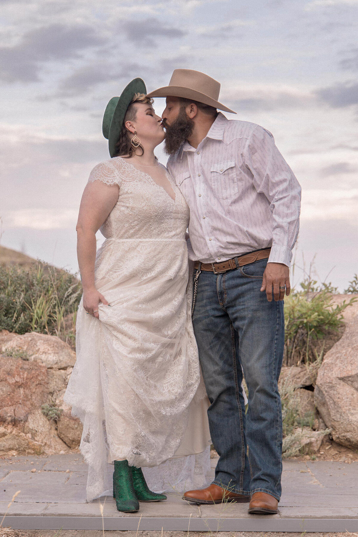 The bride kisses her groom while showing off her emerald green boots