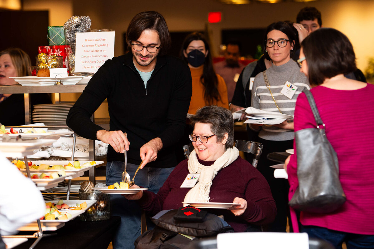 Ottawa event photos of a woman in a wheelchair being assisted with breakfast.  Captured by JEMMAN Photography COMMERCIAL during the CCRAW 2-day corporate conference