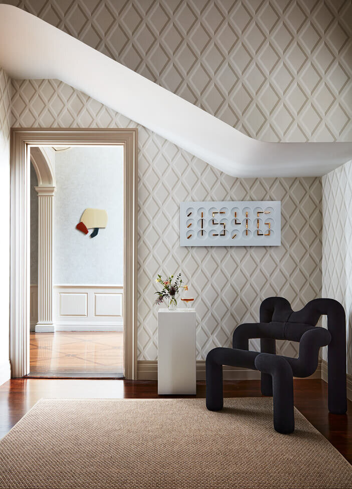 A historic home in Boston features geometric wallpaper and a sculptural modern chair, blending bold patterns with refined interior design.
