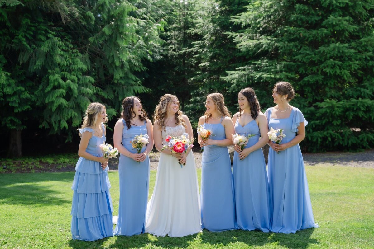 bride with bridesmaids in light blue dresses laughing