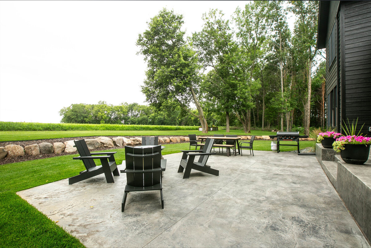 Exterior view of custom home in Otsego, Minnesota with black siding, large patio and windows built by Cornerstone Custom Builds