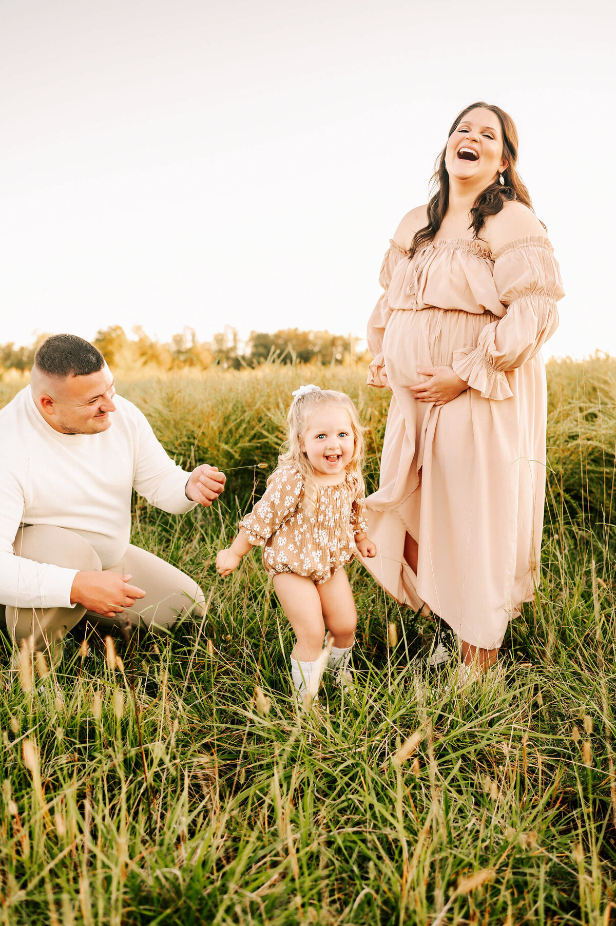 pregnant mom laughing with family outdoors during Springfield MO maternity photography session