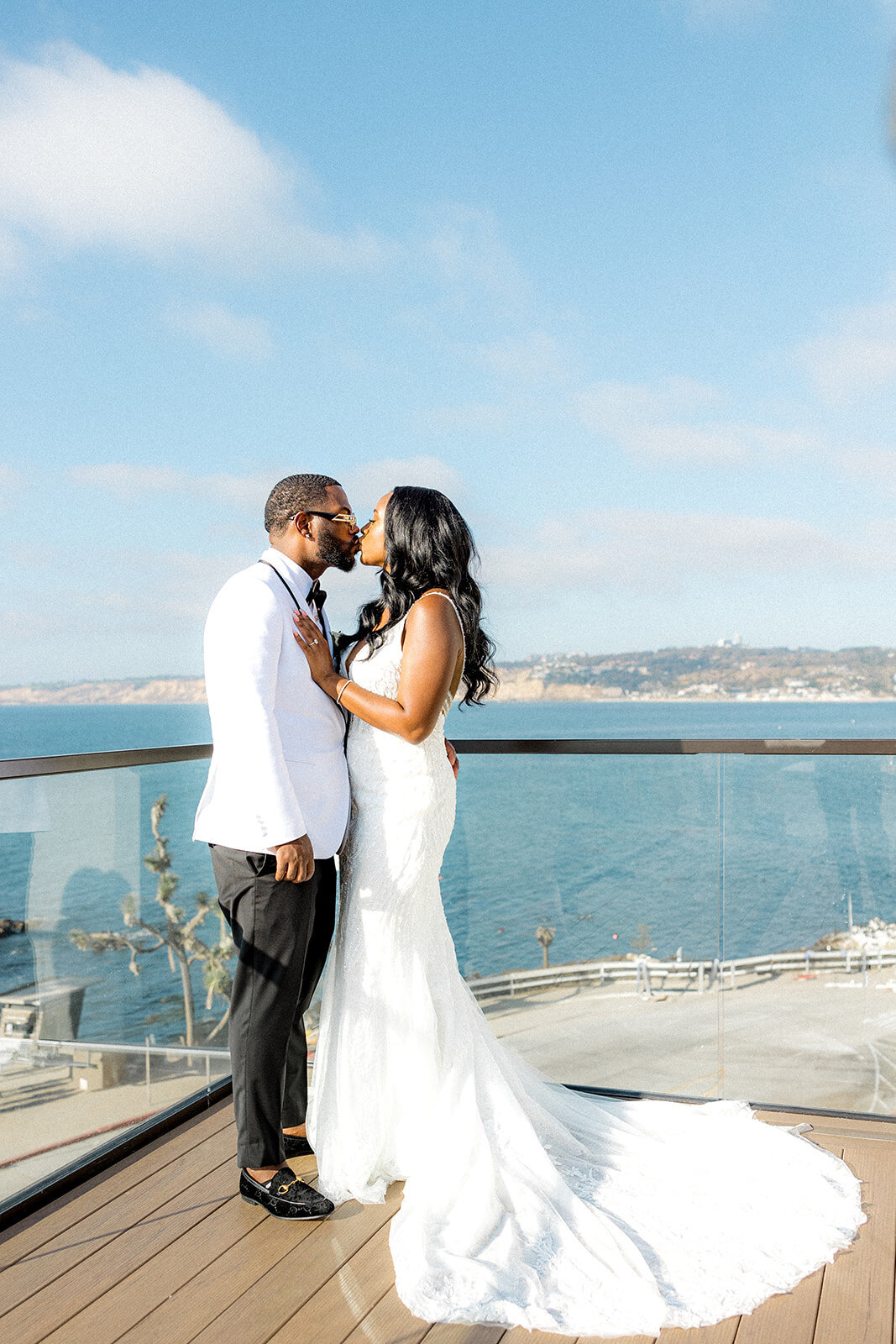 Bride and groom kissing on balcony in San Diego with ocean in the back