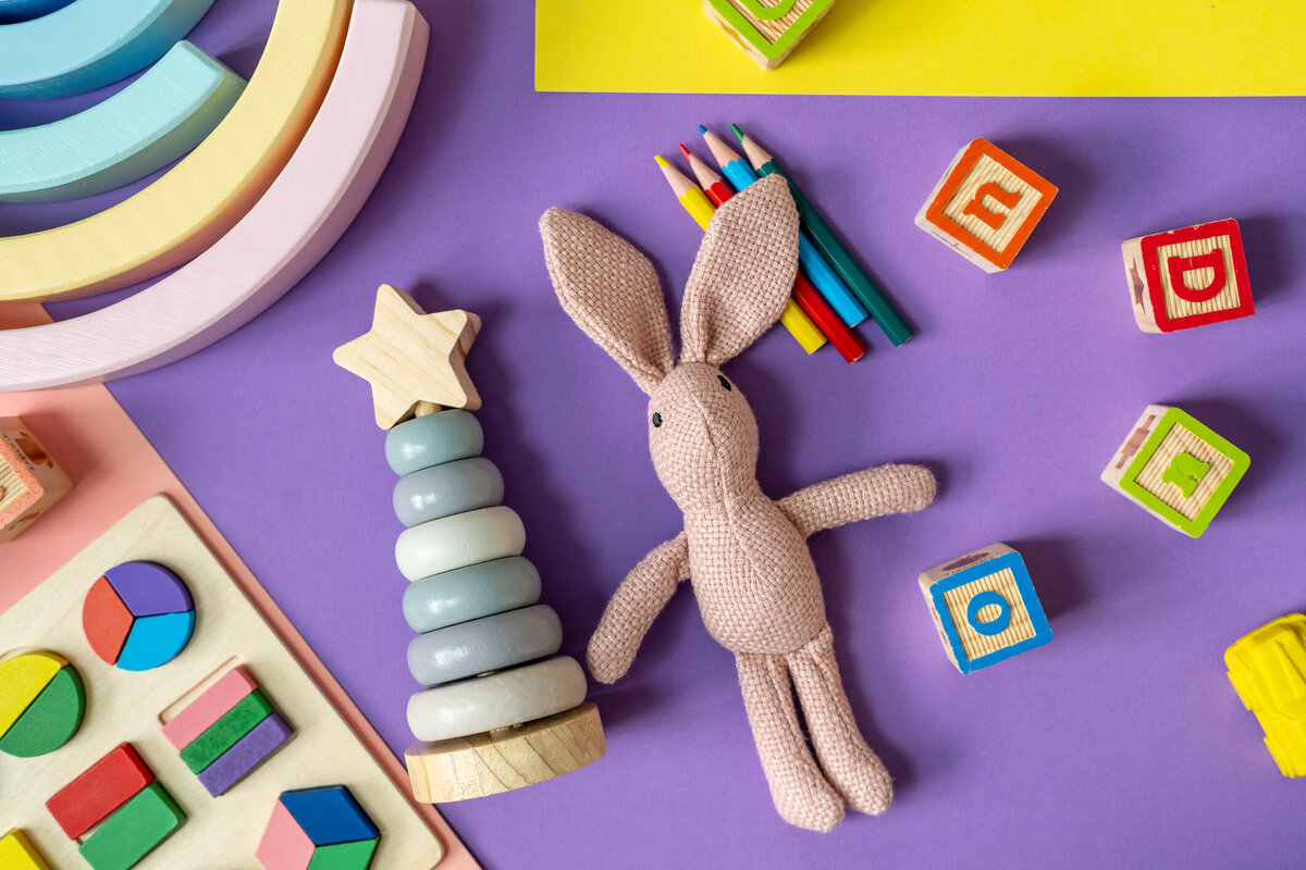 Purple background with blocks, crayons, stuffed bunny  and other children's toys