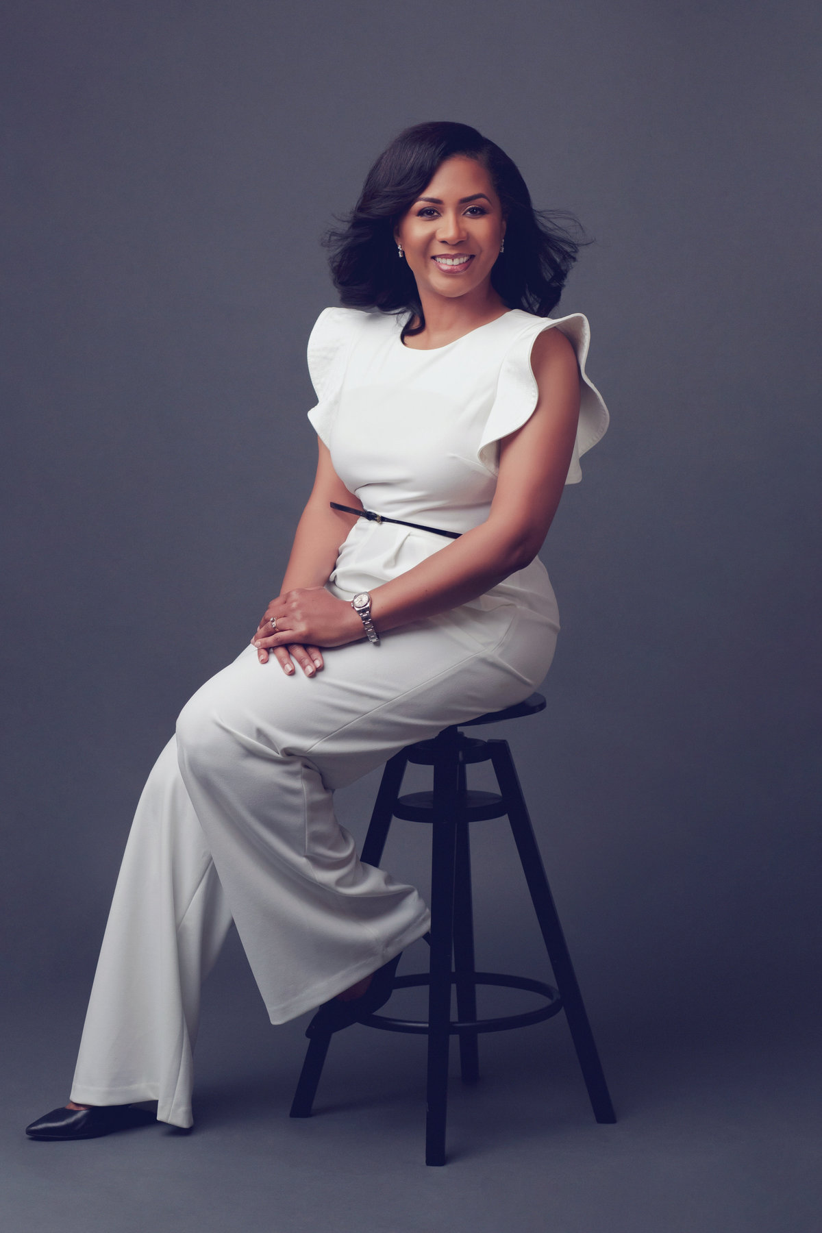 Woman sitting on a stool, facing the camera. Houston, TX Luxury Portrait.