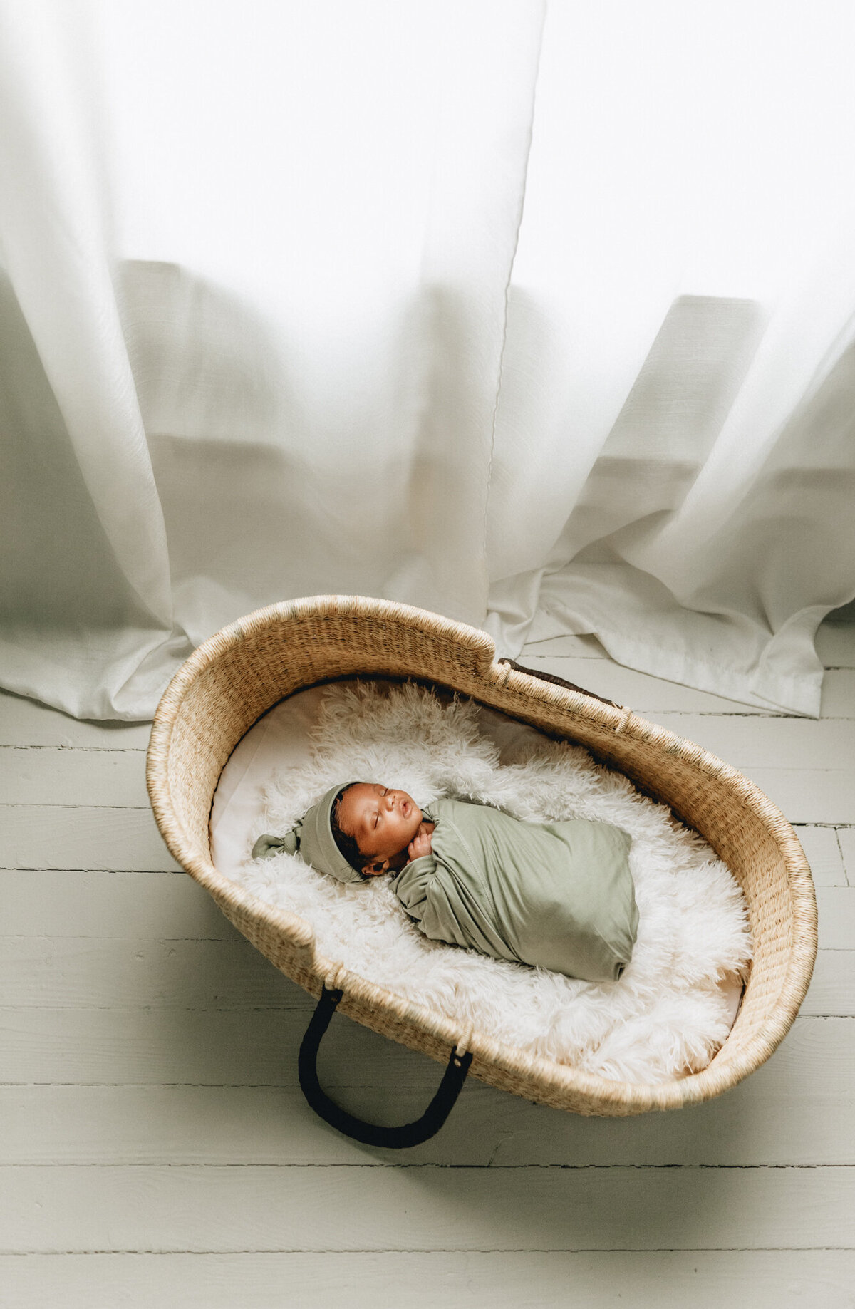 Infant photographer capturing newborn baby sleeping in a crib.
