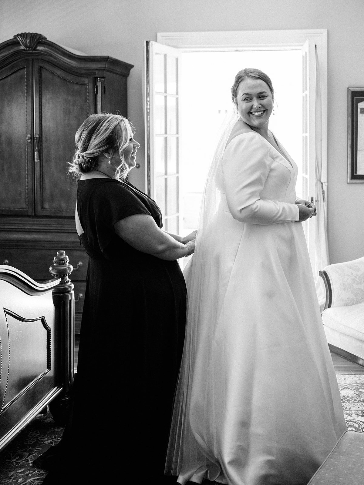 Bride  getting dress zipped up by maid of honor