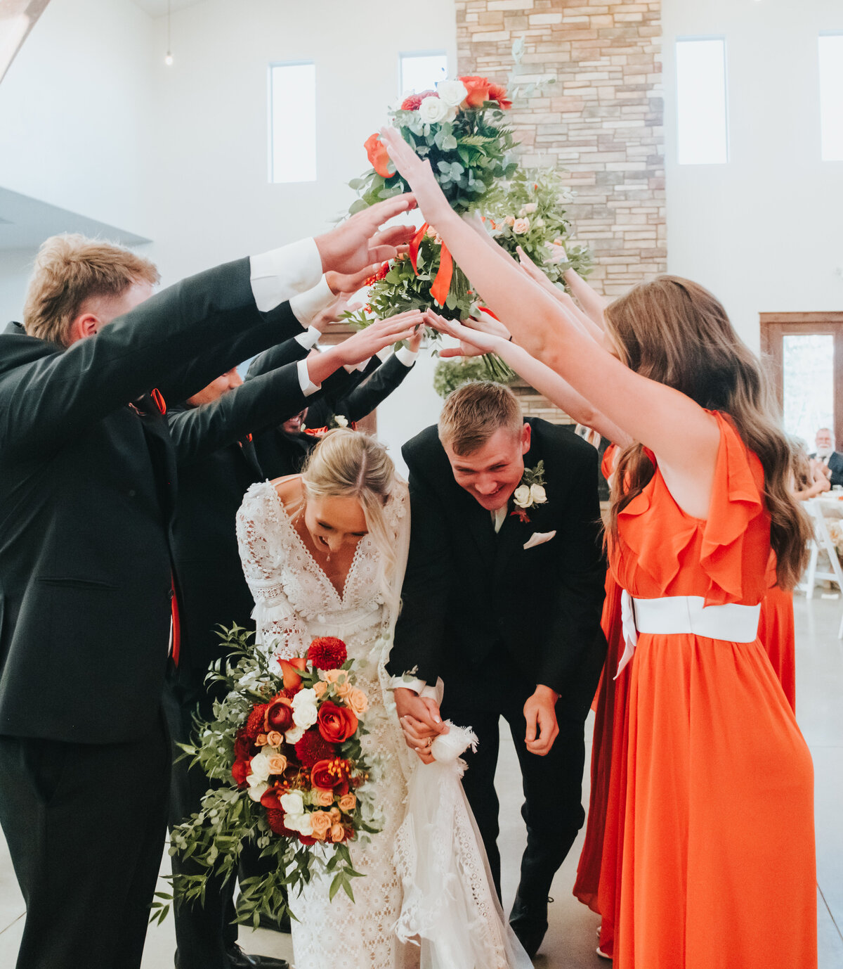 Couple running through a tunnel of the wedding party's arms
