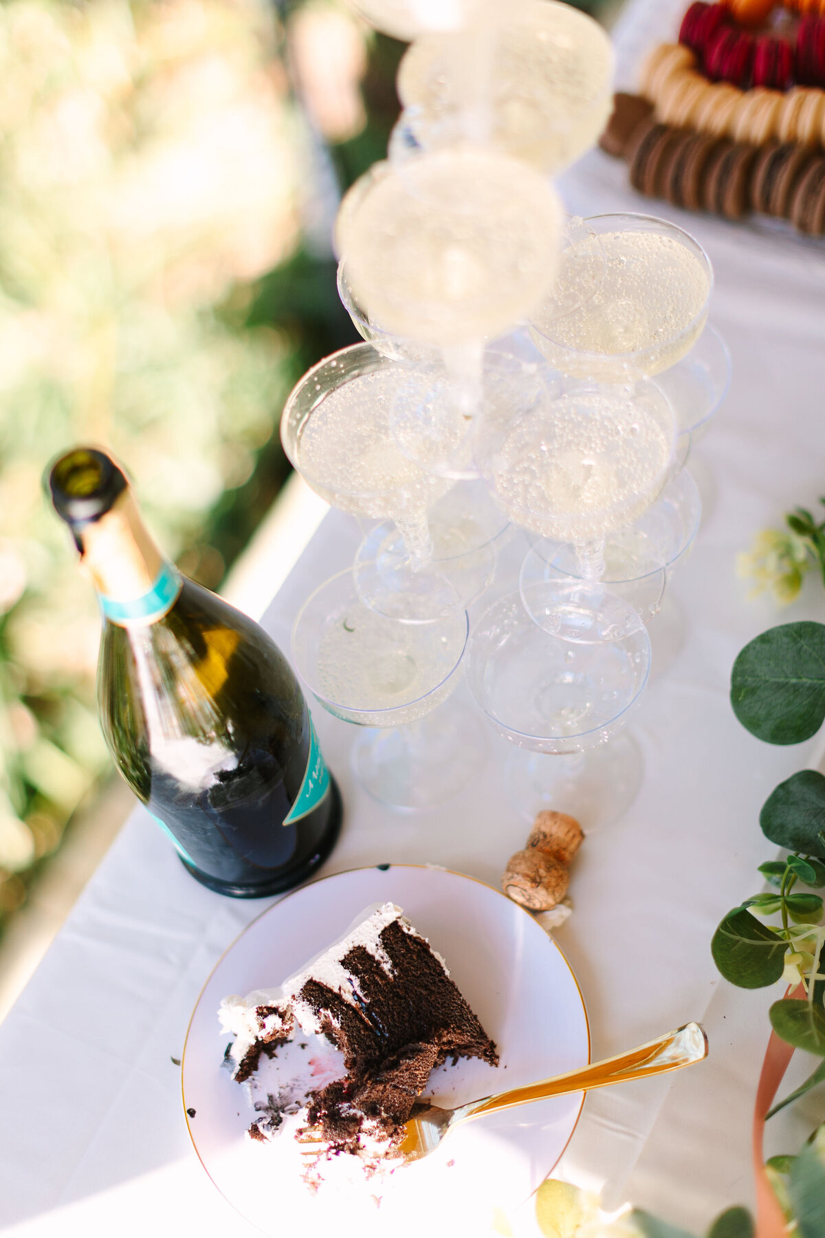 Messy wedding flatlay during reception of champagne tower, slice of cake, and details