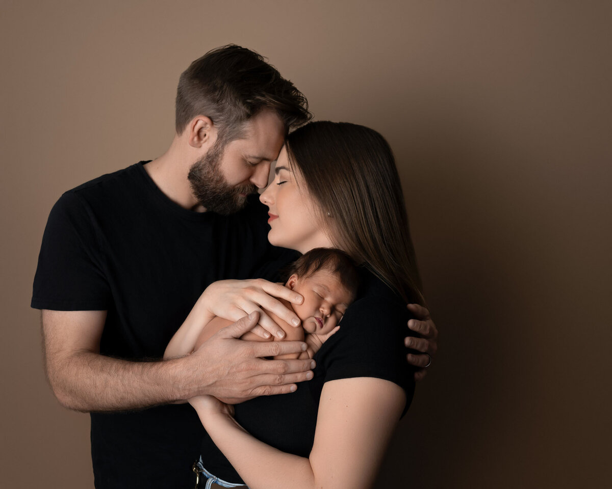 couple kissing with newborn Lakeway family portrait photographer