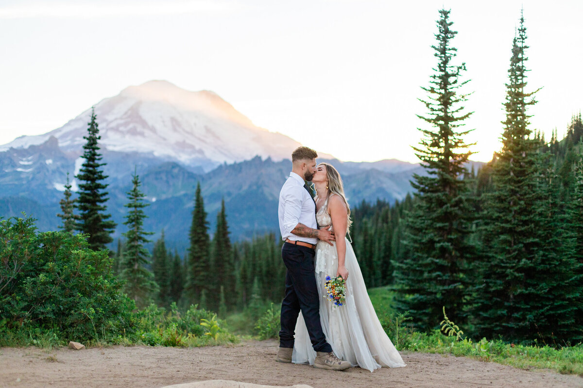 bride and groom kiss on mountain top during blue hour