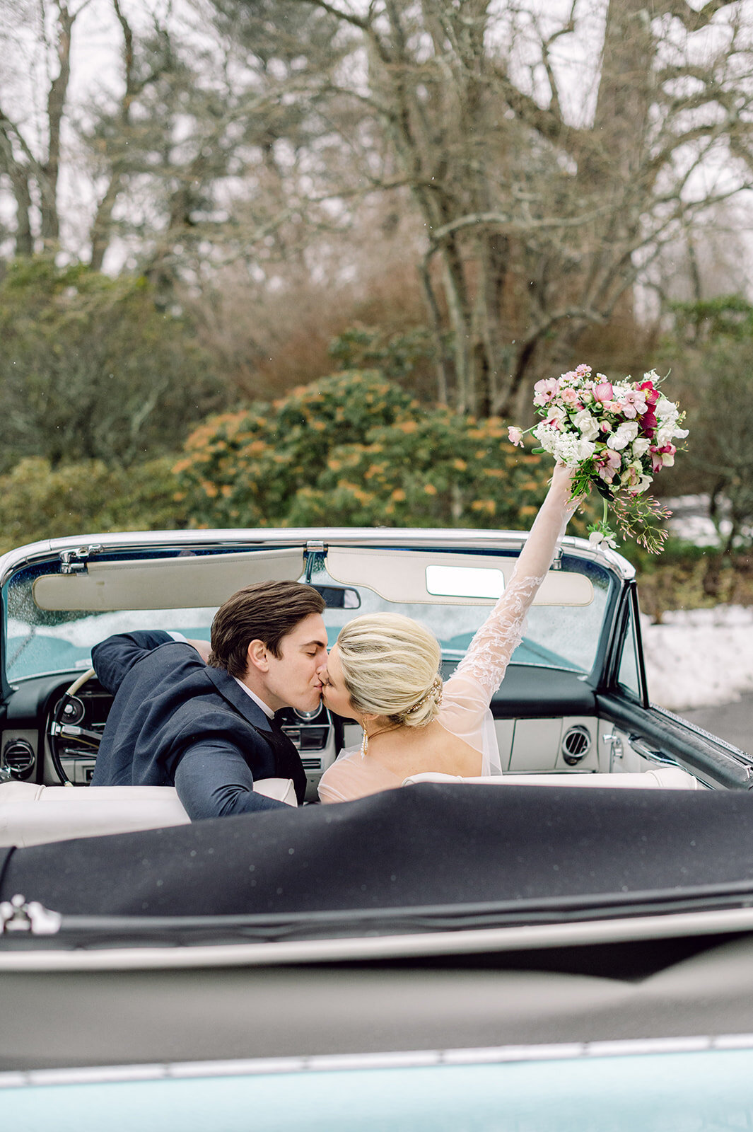 Bride and groom kiss in getaway car