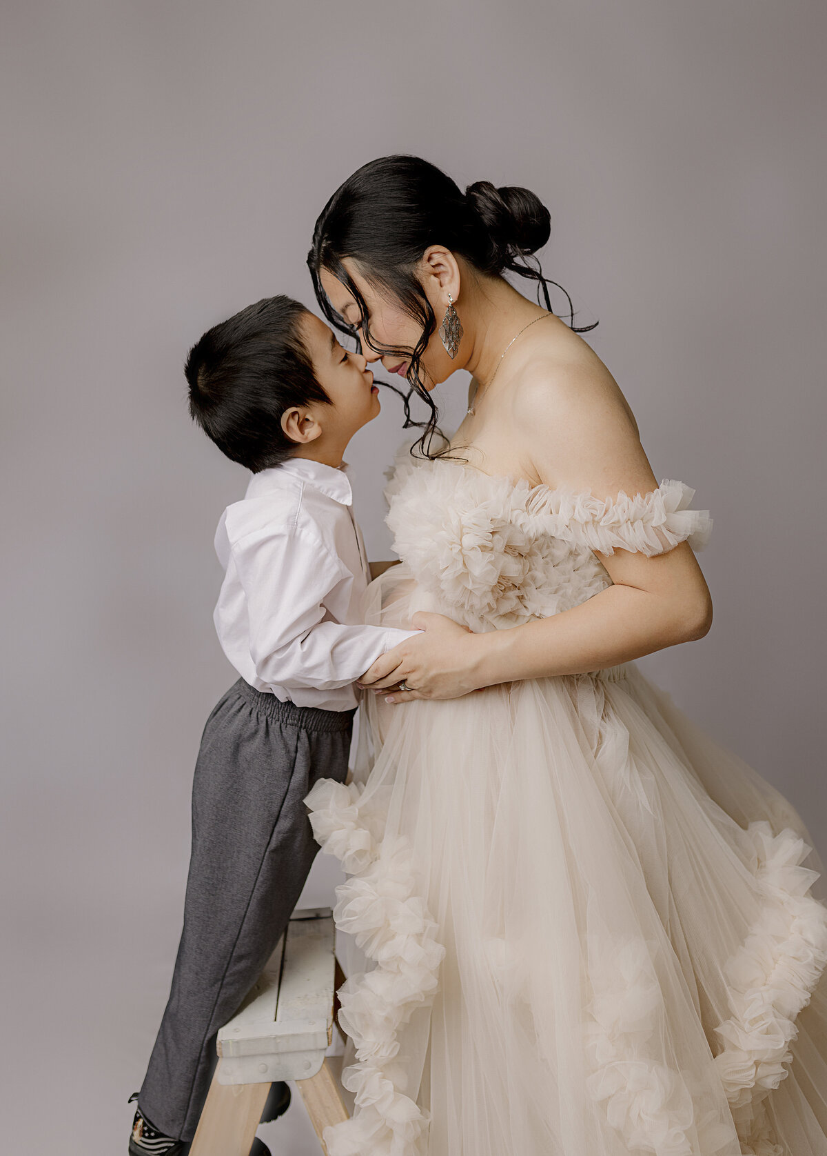 mother and son holding noses together on white backdrop