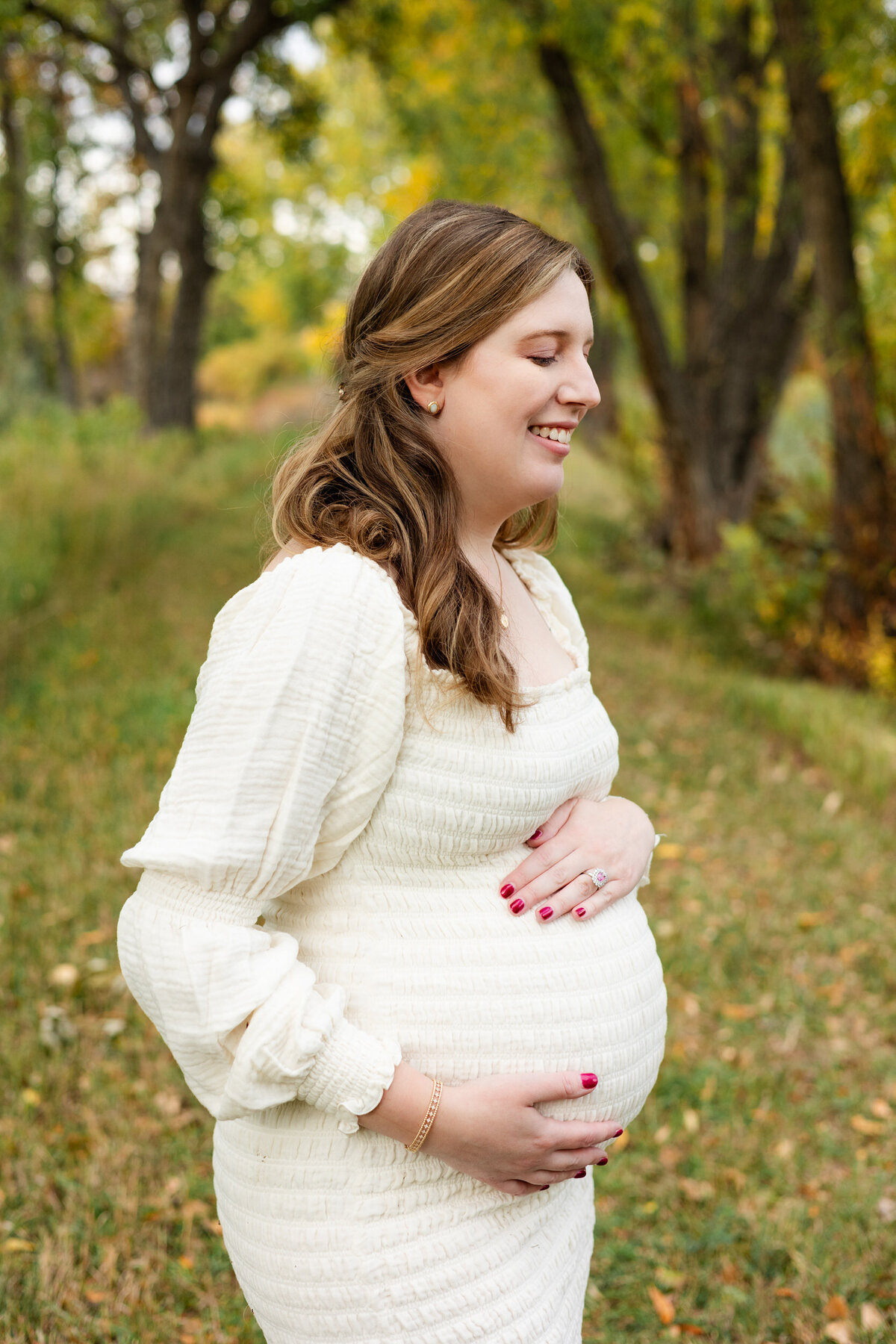 Pregnant woman holding her belly and smiling down at her bump.