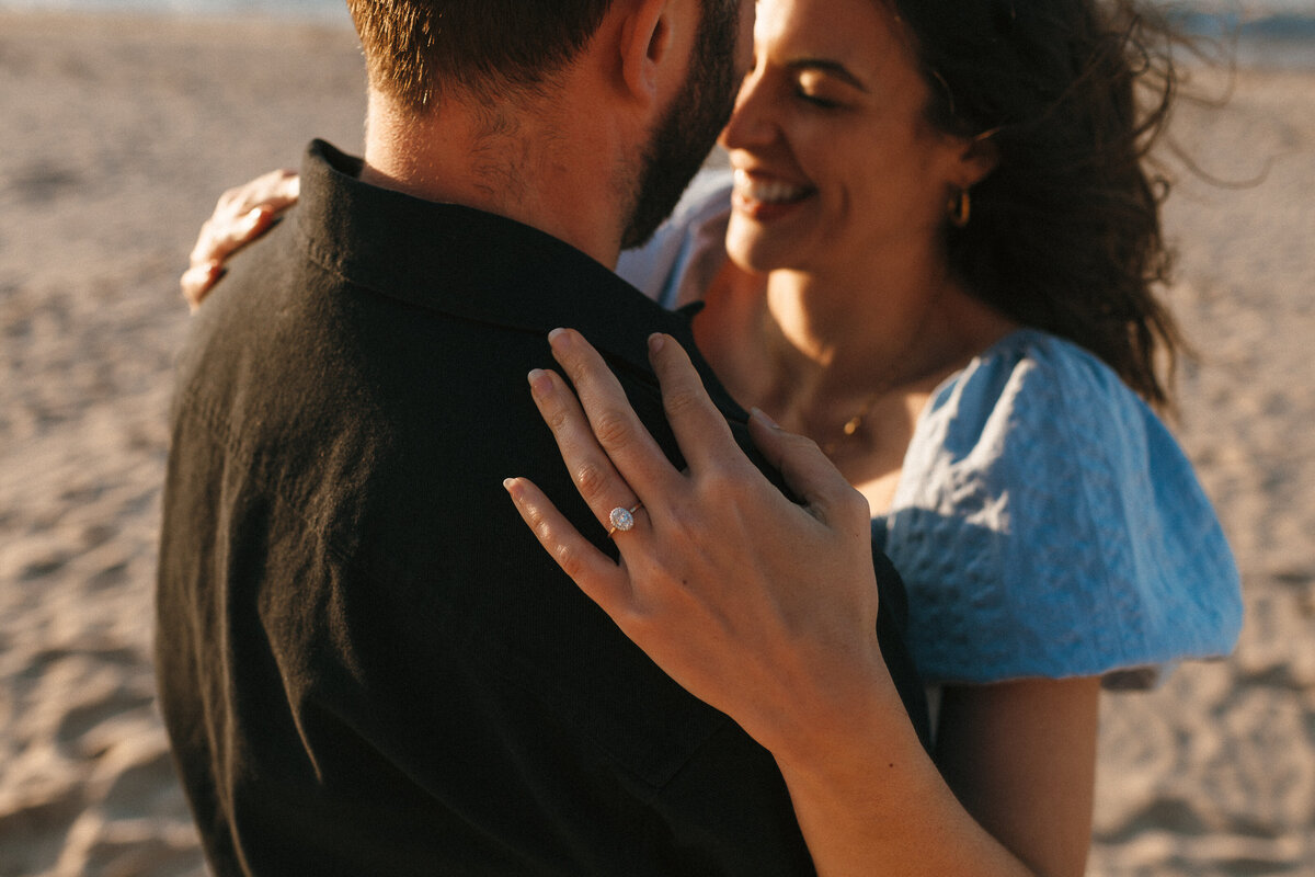 Engagement shoot photo at sunset on the beach in Cornwall with the engagement ring in focus