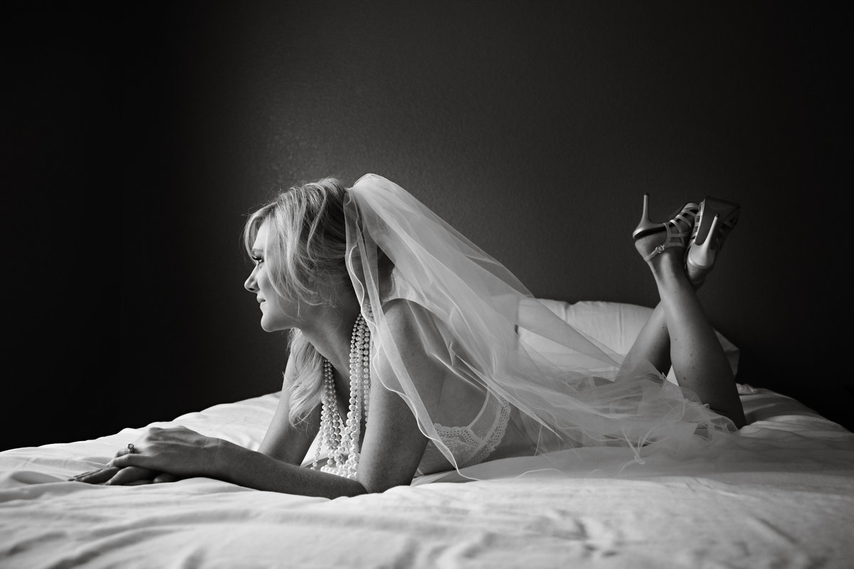 Bride to be lying on bed with her veil and bridal lingerie on