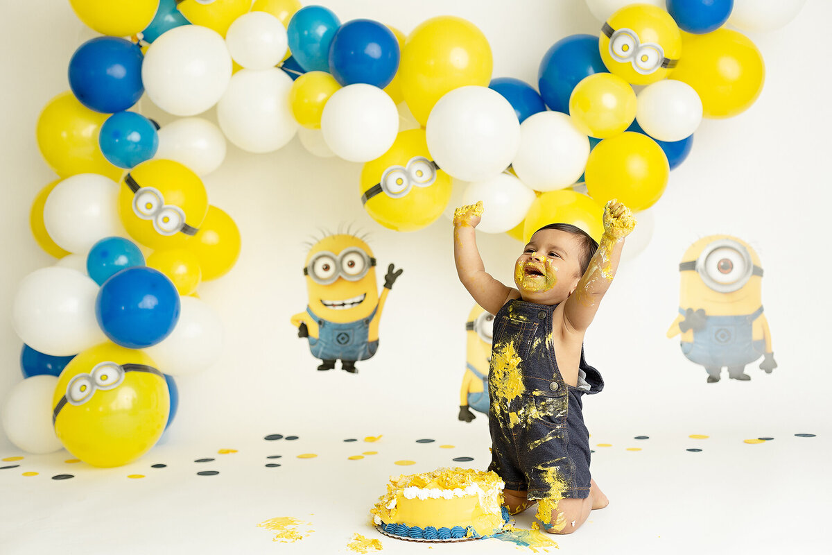 columbus-ohio-baby-boy-in-blue-overalls-smashing-cake-for-first-birthday-minions-movie-cake-smash