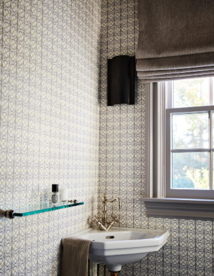 Milton kitchen and bath designer creates a powder room in a classic Milton home with a modern Kelly Wearstler light, Quadrille wallpaper, and a light grey palette.