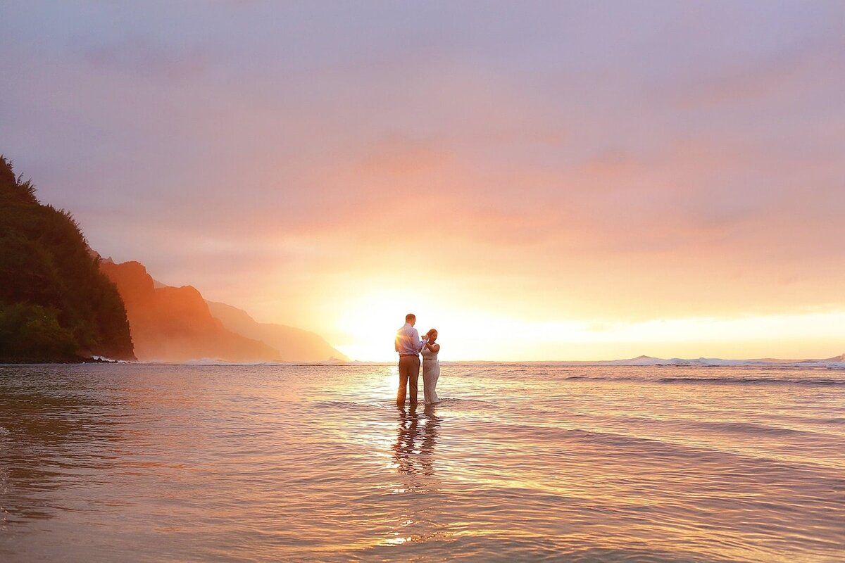 Couple hold hands and dance at low tide on a beach on Kauai as photographed by Love + Water