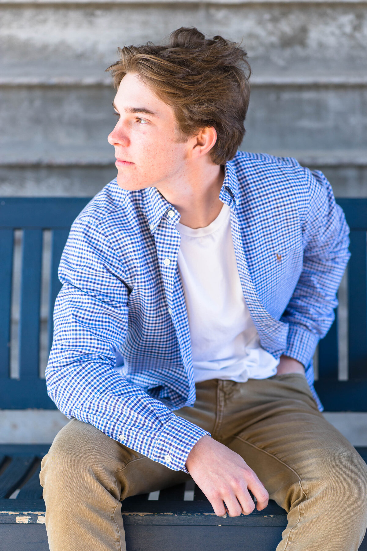 Senior boy sitting on blue chair in blue shirt