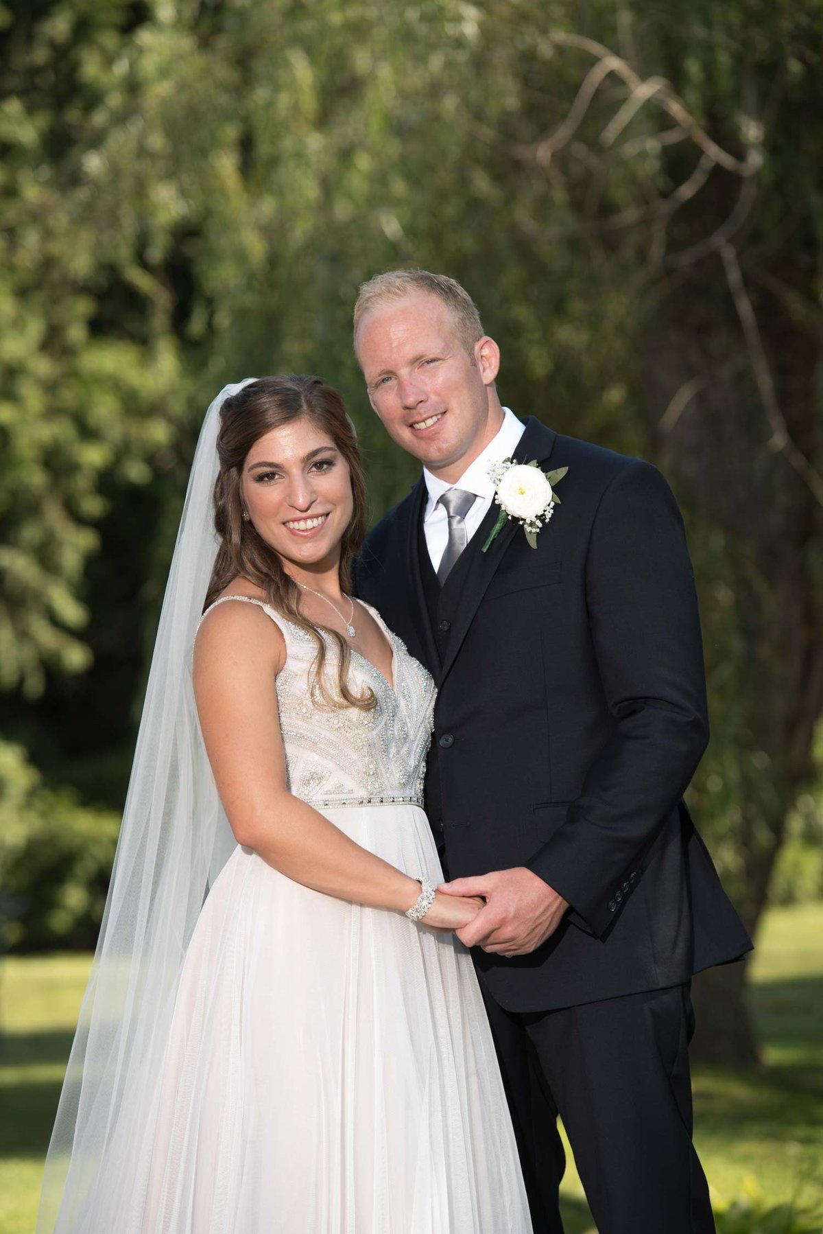 Brie and groom smiling and holding hands outside at Flowerfield