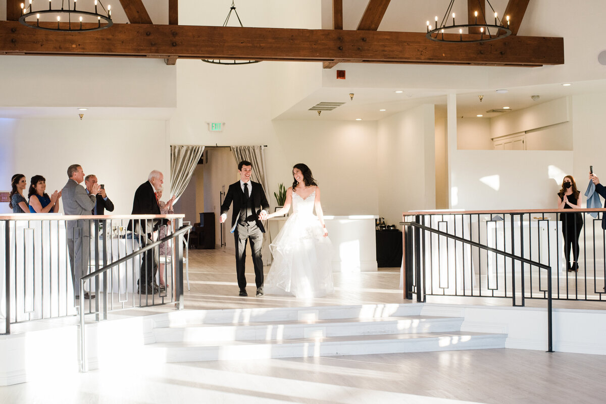 Denver wedding photographer captures bride and groom dancing into the reception space for the grand entrance at The Oaks