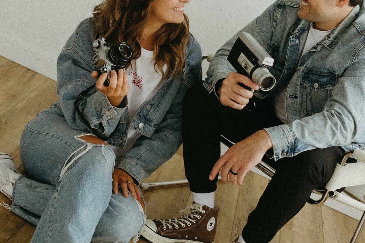 Close-up of Alberta photographer and videographer duo Hannah and Tyler holding a digital camera and a Super 8 video recorder.