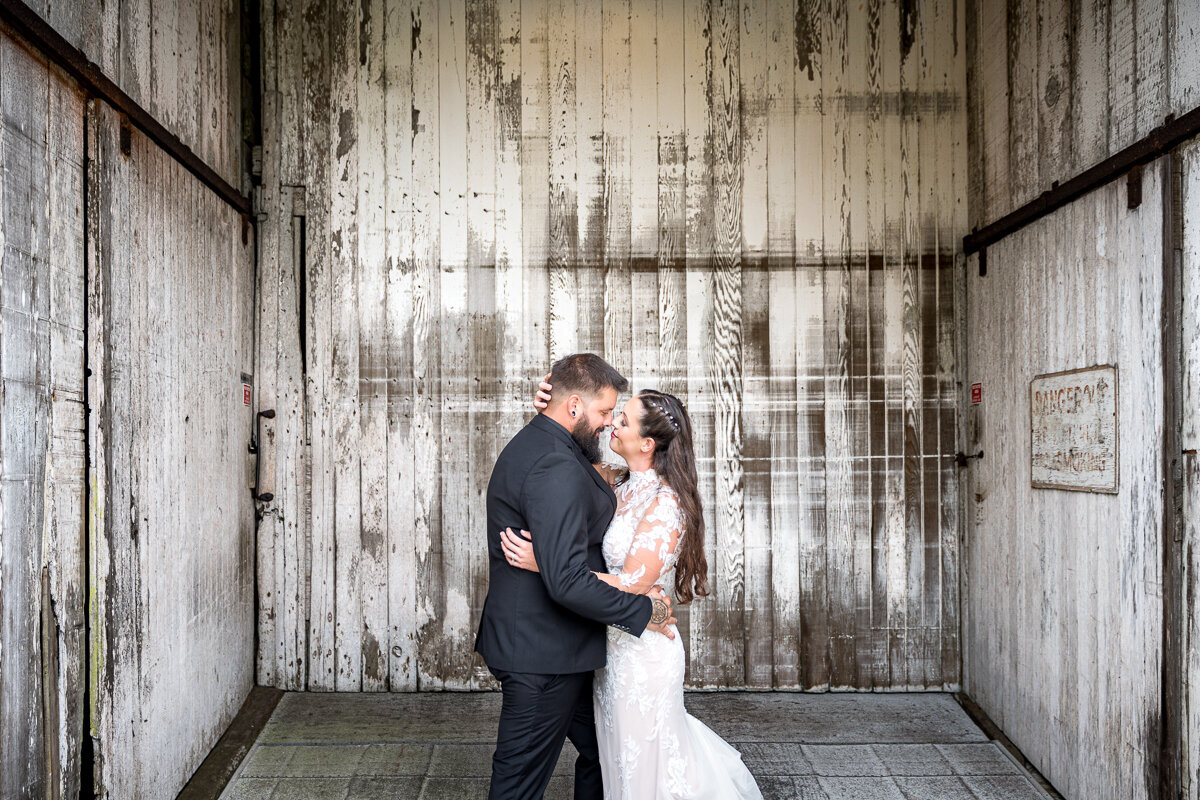 A romantic wedding portrait of a bride and groom sharing a kiss in front of the rustic barn doors at North Coast Hitching Post in Loleta, CA, capturing the charm and love of their special day.
