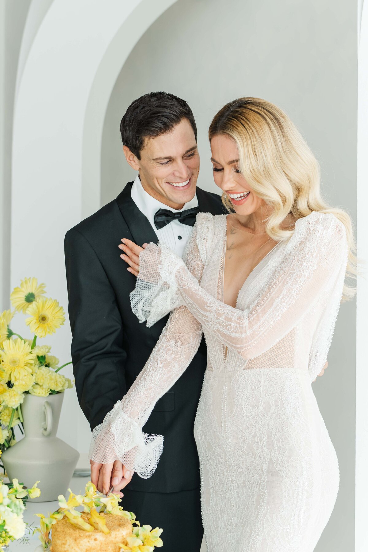bride and groom cutting their cacke while smiling