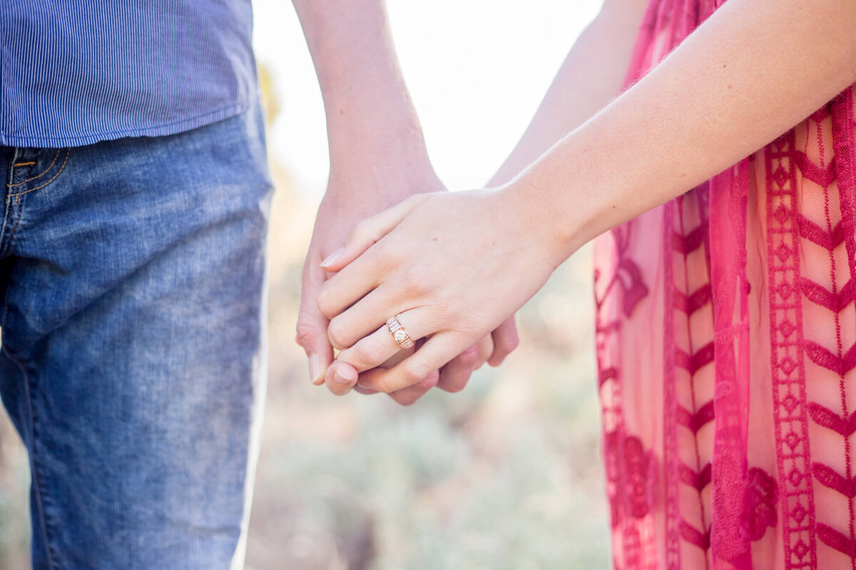 a couple holding hands showing off their relationship and engagement ring