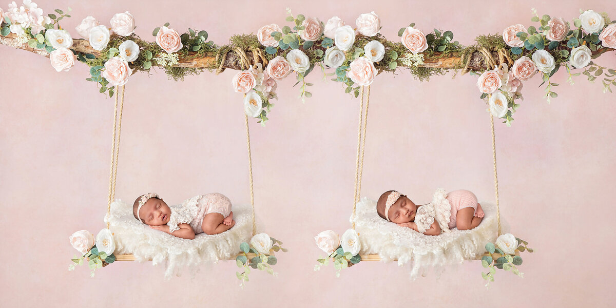 Twin newborn girls posed on matching floral-decorated swings, each sleeping on a soft cream layer against a pink backdrop.
