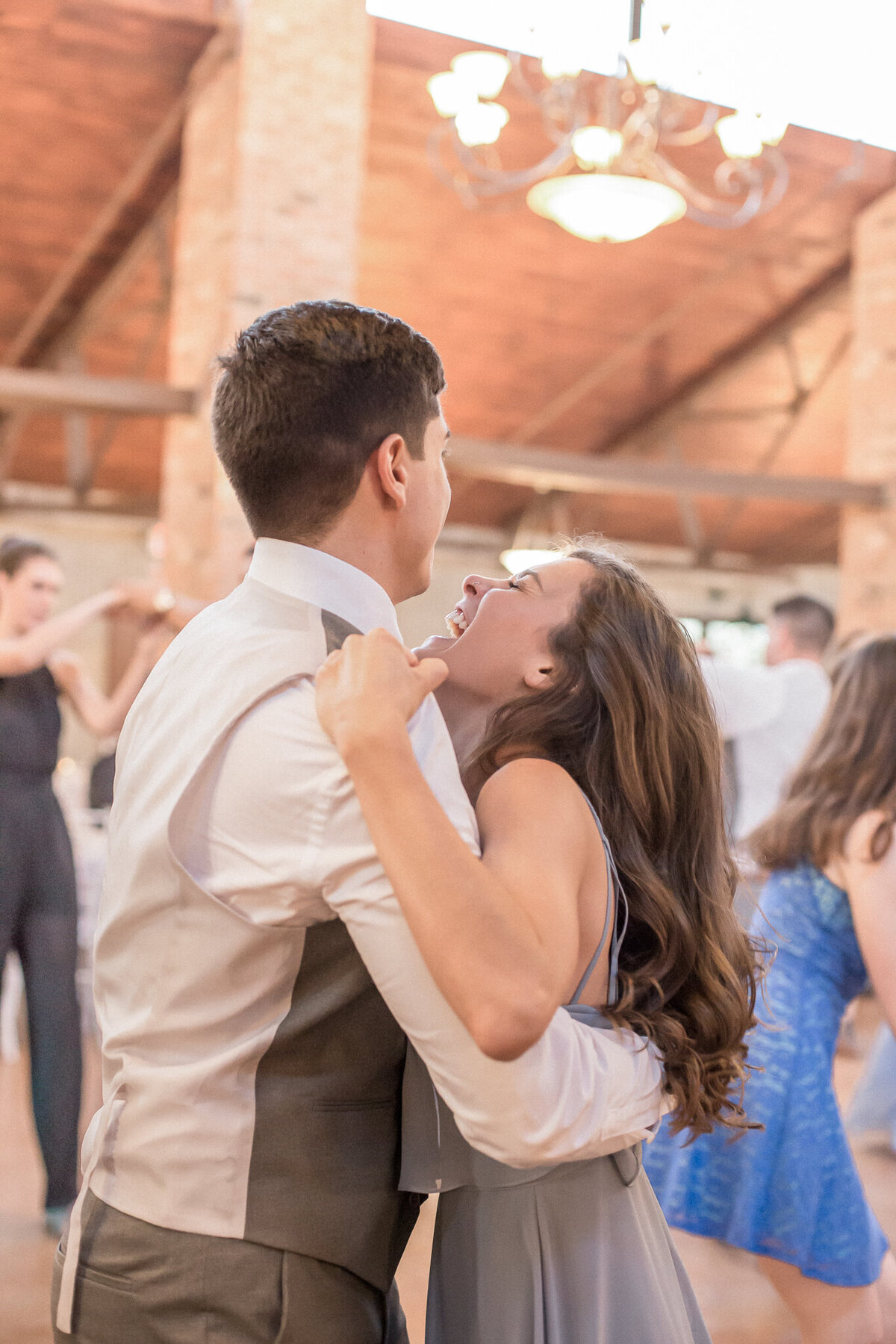 The maid of honor, smiling joyfully, dances with the best man.