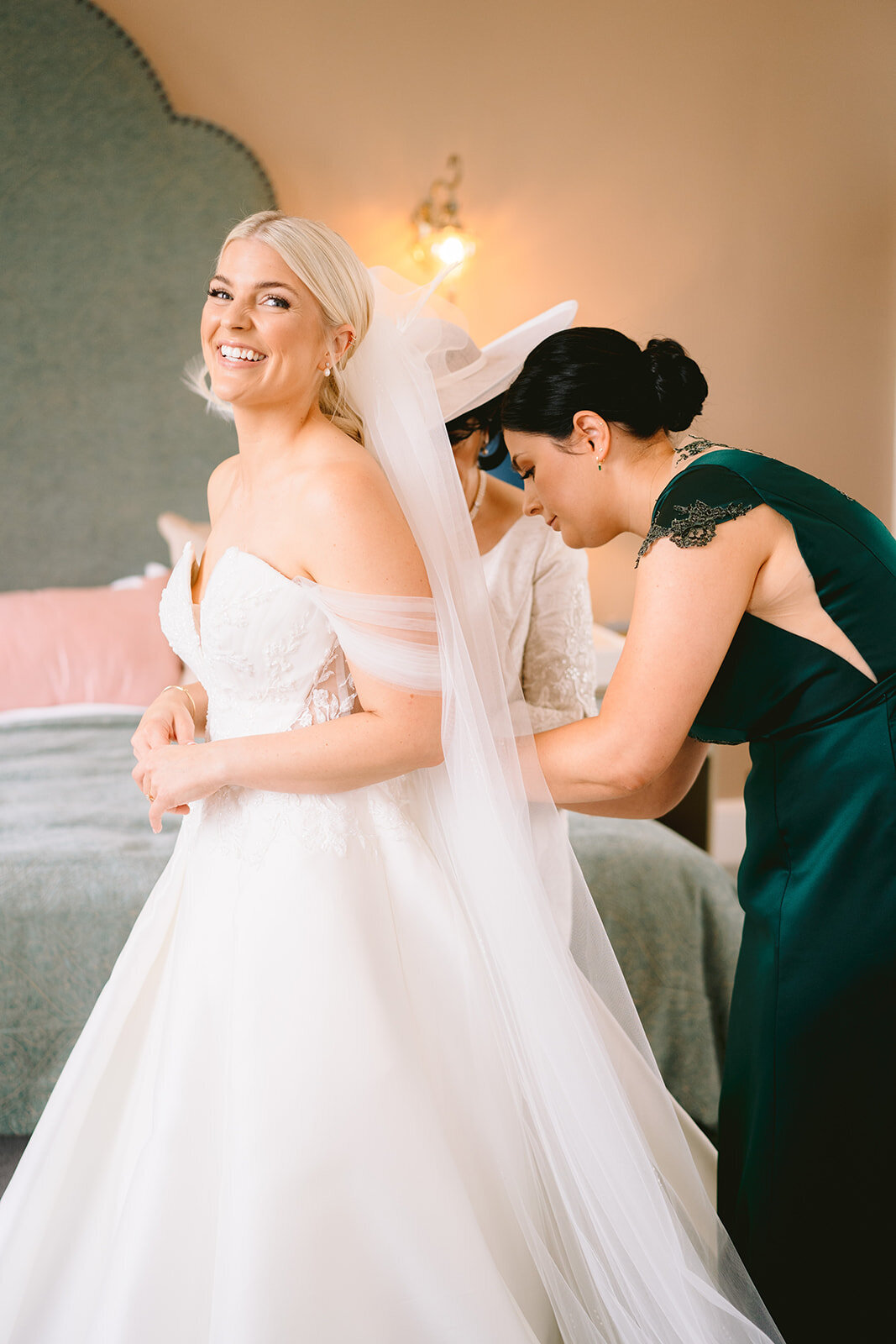 bridesmaid putting bride into the wedding dress in the bridal suite at hawkstone hall