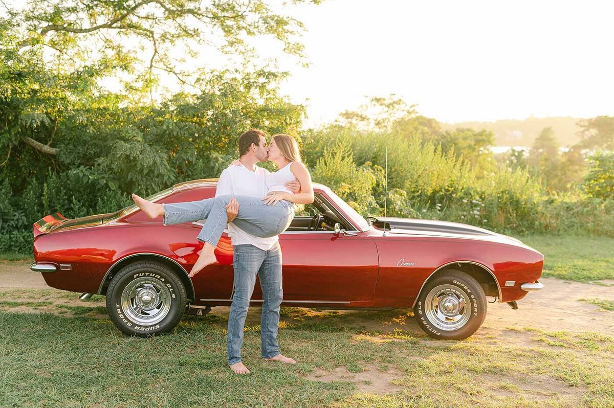 couple kissing in front of red mustang charger