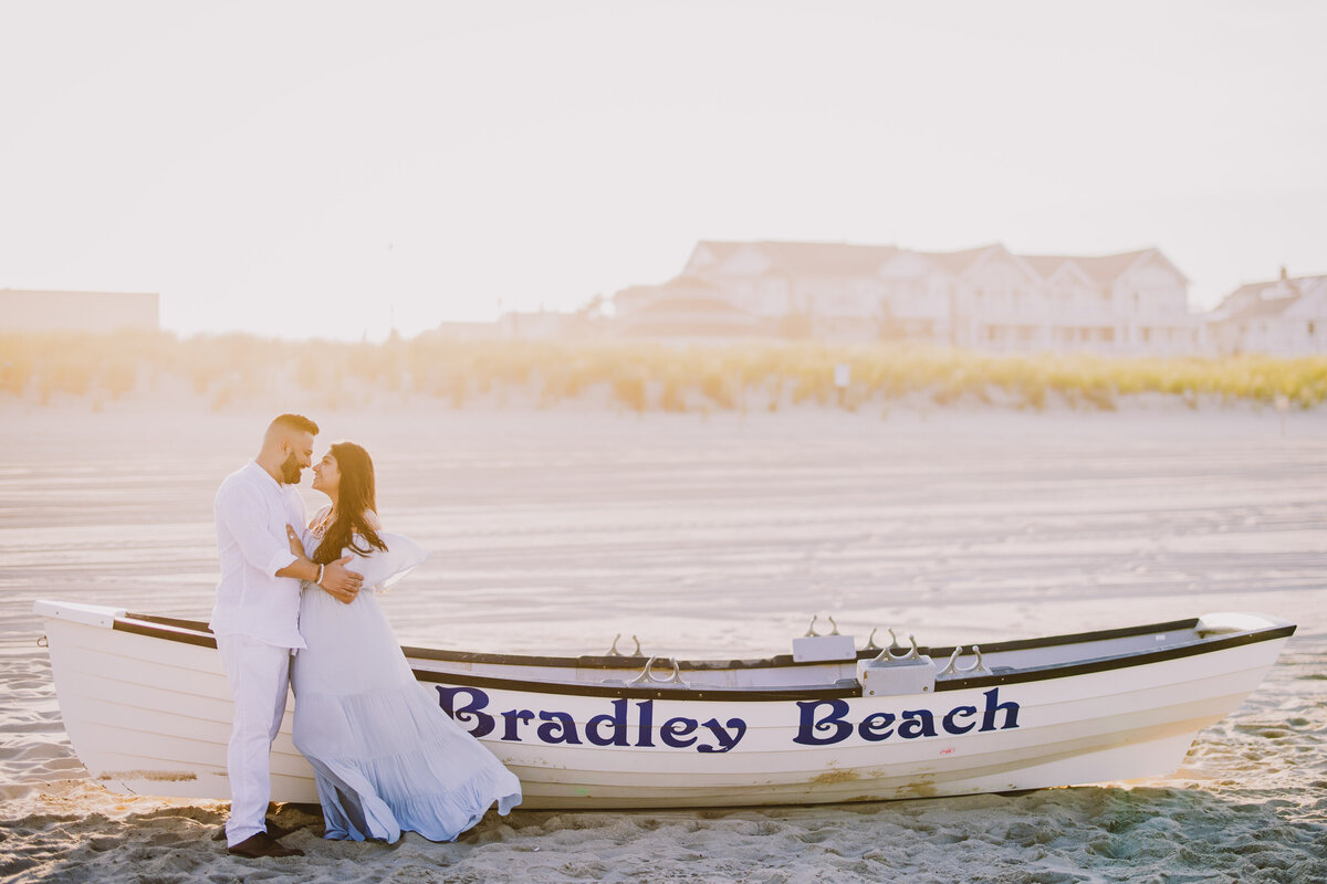 A couple sharing a moment in front of a big bradley beach canoe on the beach at sunset