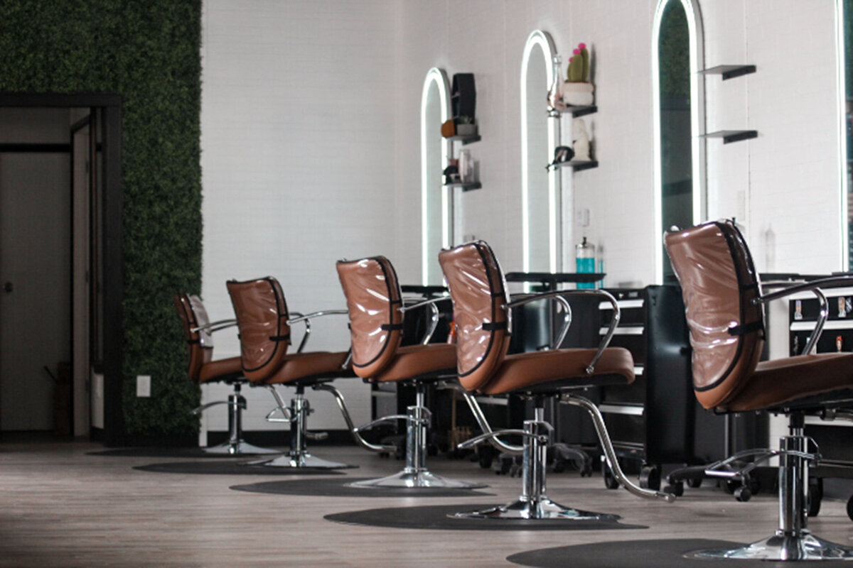 A row of salon chairs with salon stations in the background