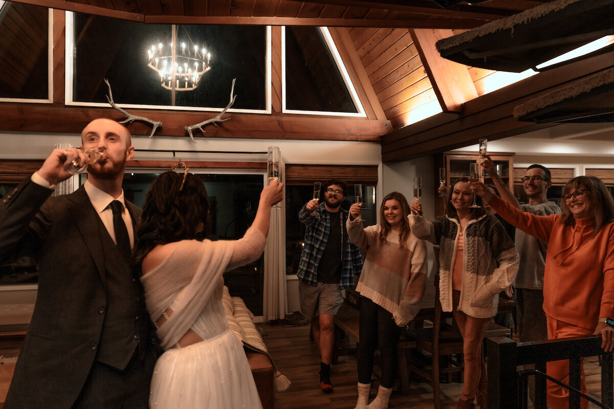 Newlyweds share a champagne toast with their group of family and friends that gathered for their micro wedding in their cabin Airbnb