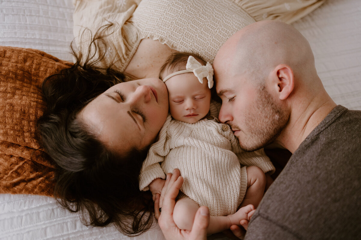 Mother and father snuggling with their newborn baby girl.