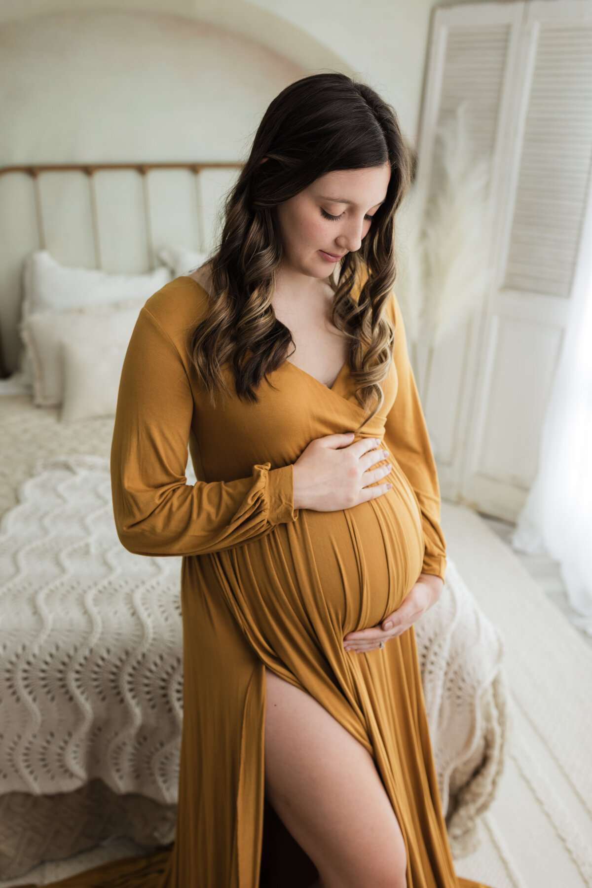 pregnant mother in gold maternity gown holding baby bump for studio maternity photoshoot cleveland maternity photographer