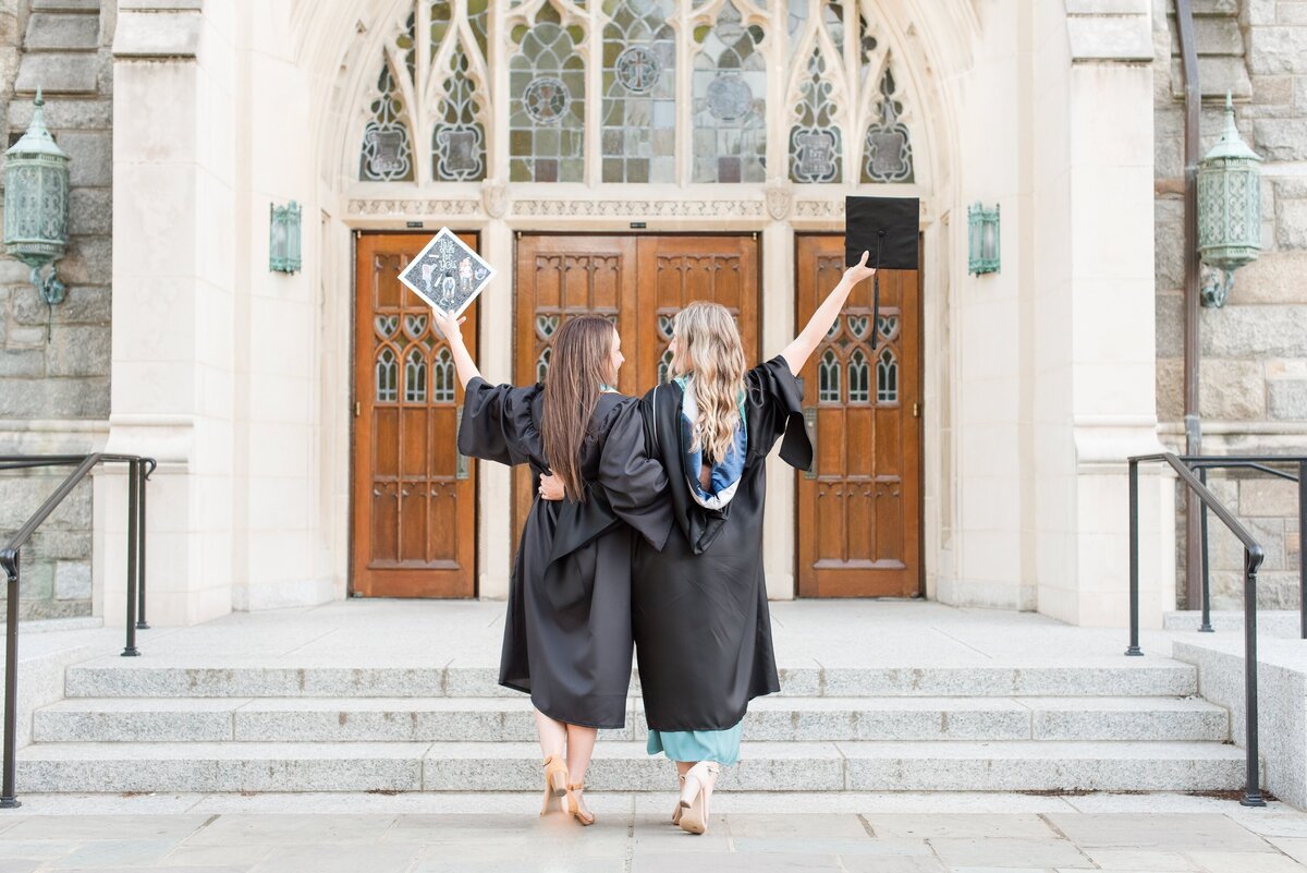 twin sisters in regalia graduation holding caps