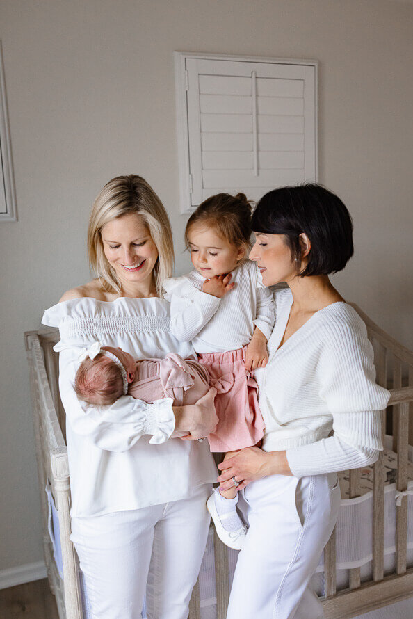 Family of four looks at their new baby during their session with Angela Marie Media.