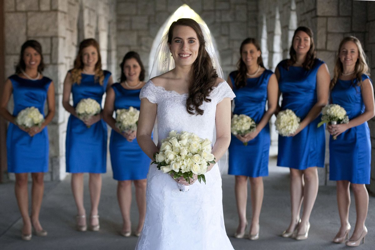 bride standing in front of bridesmaids in royal blue dresses