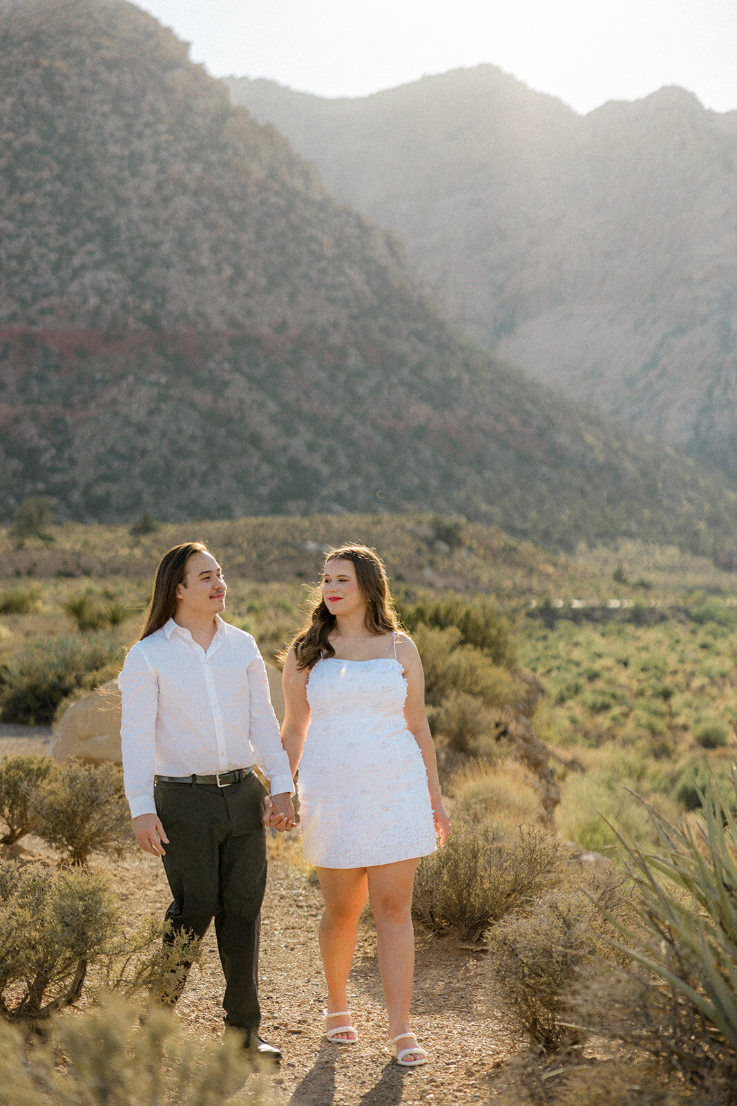 Engaged couple walking with mountains in the background in Nevada