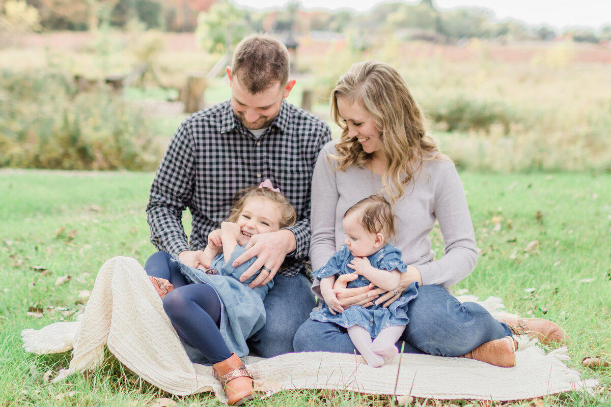 family sitting on the ground laughing and tickling each other