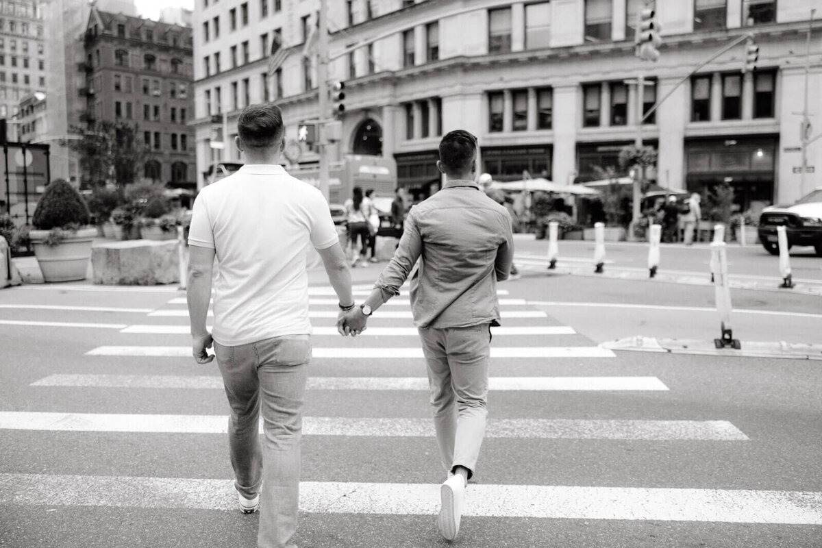 Black and white, back view photo of the engaged couple crossing the street in West Village, NYC. Image by Jenny Fu Studio.