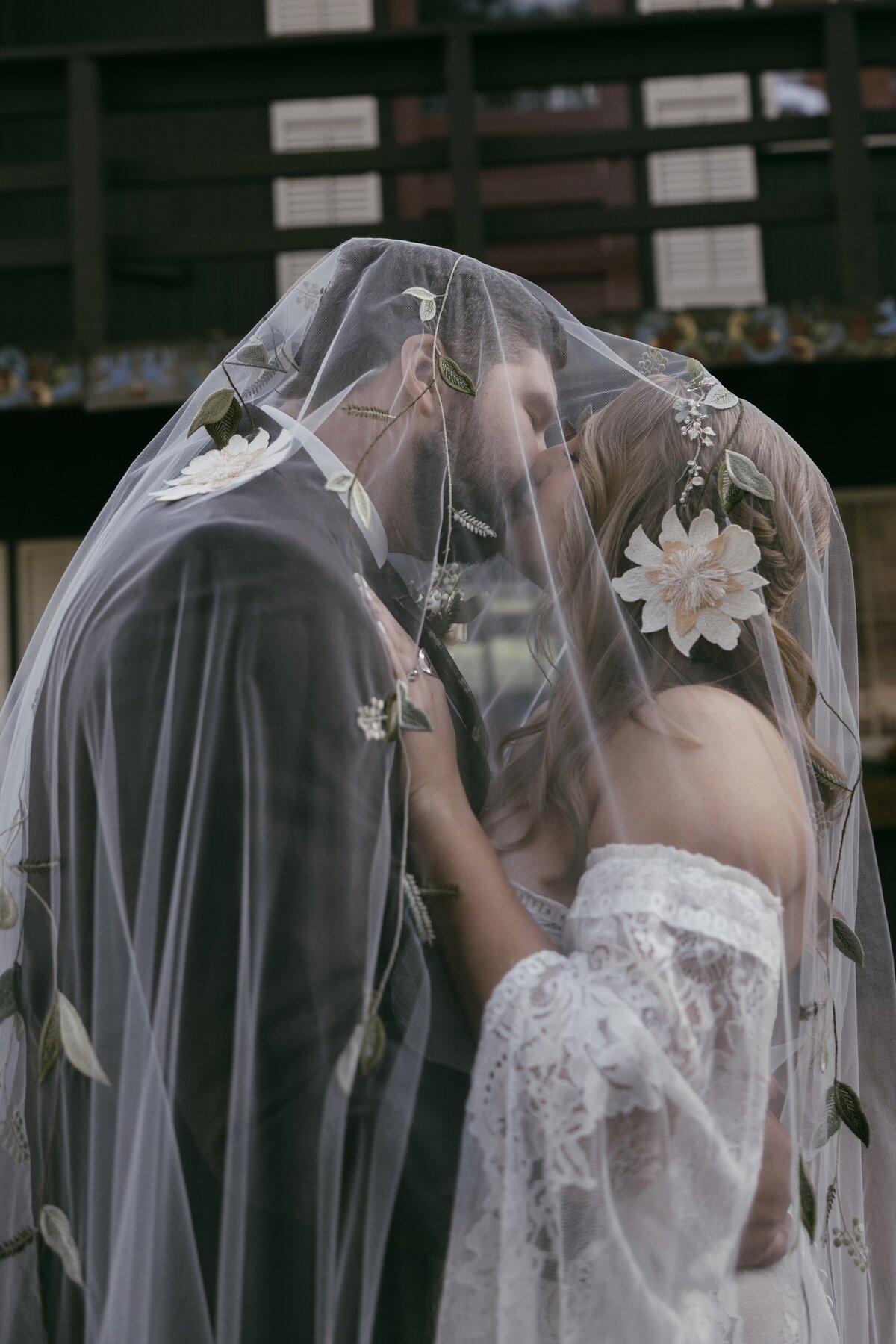 Gorgeous, elegant and vintage looking wedding photography of bride and groom kissing, with the bride’s veil draped in flowers, covering both of their heads captured by Morgan Ashley Lynn Photography in Madison, WI