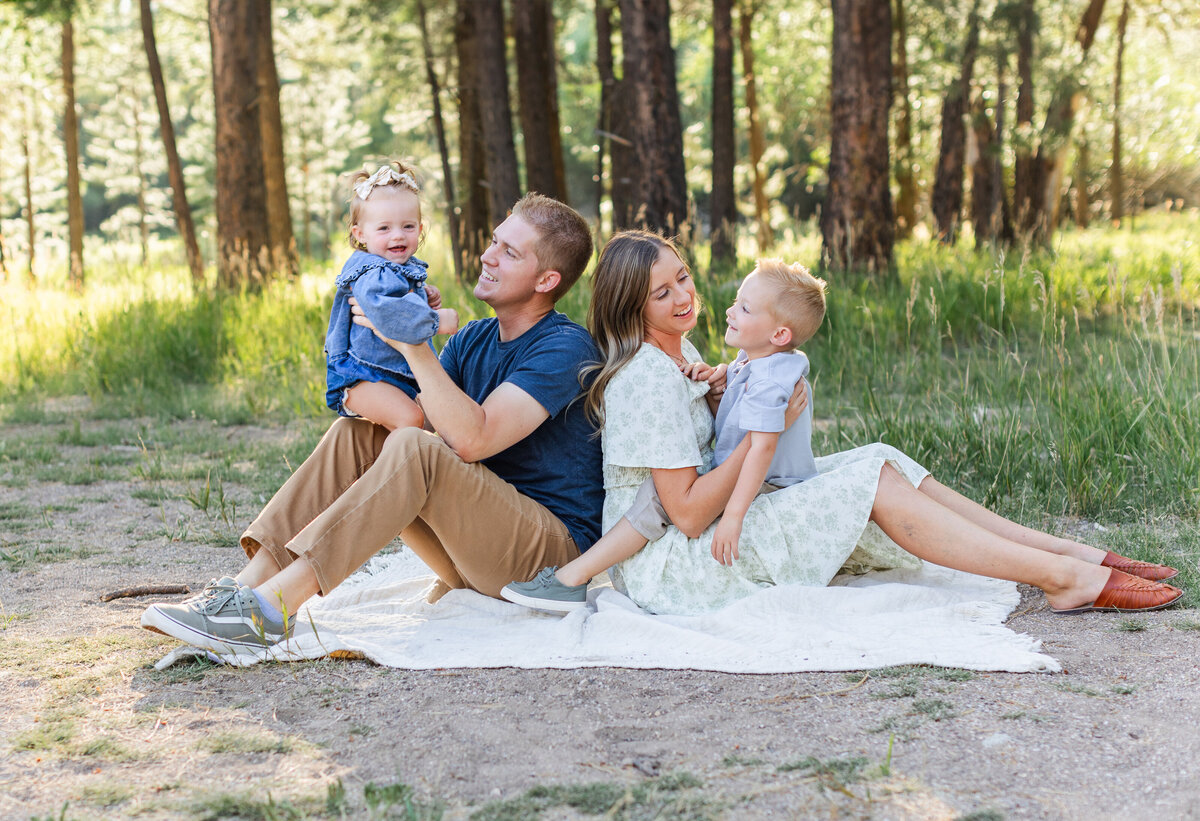 mom and dad and kids playing a game with a blanket