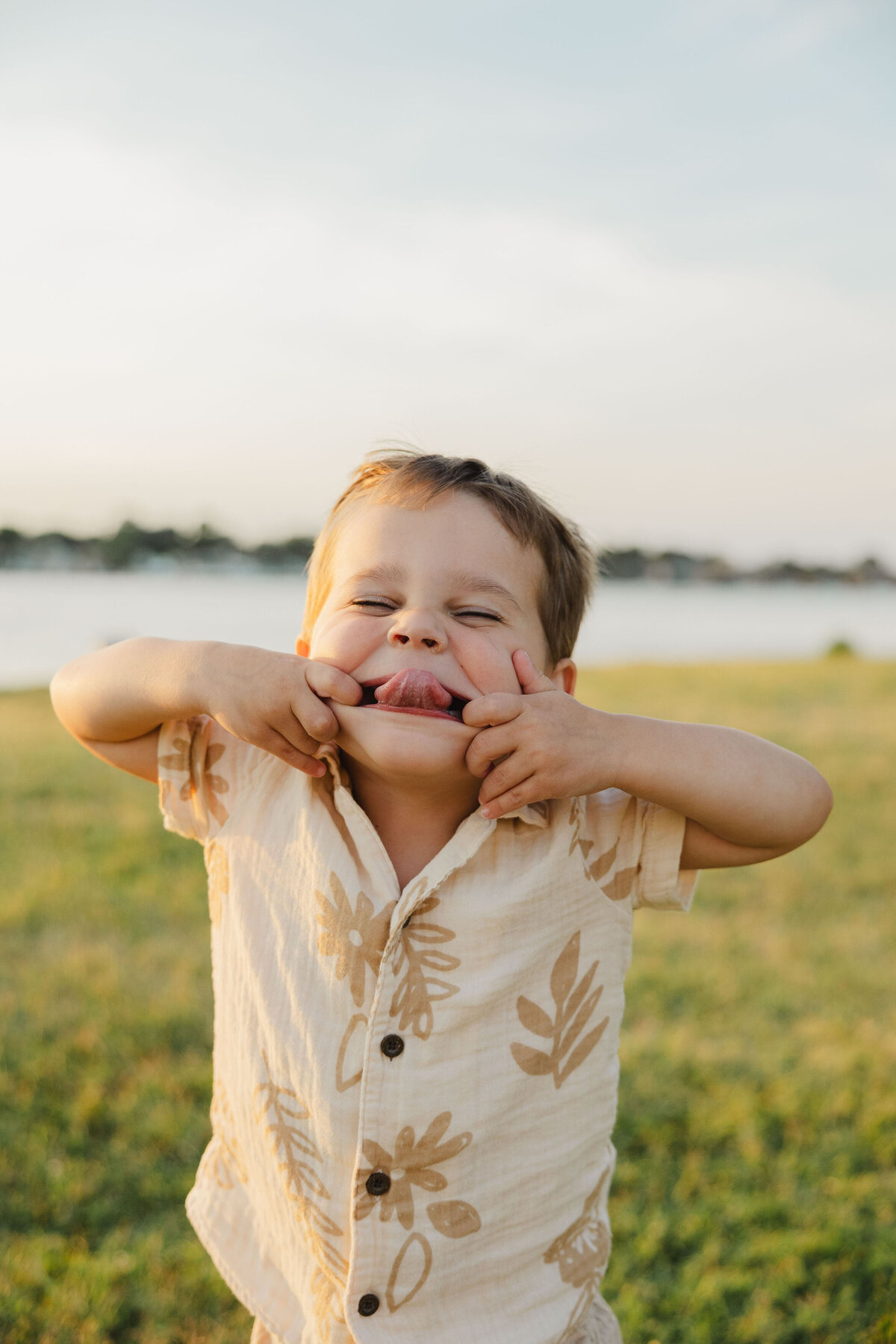 A child makes a funny face while sticking their tongue out near the water.